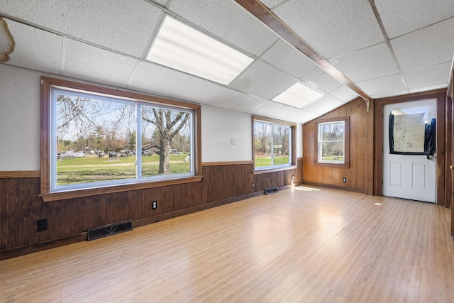 spare room featuring a drop ceiling, wood walls, wood finished floors, and visible vents