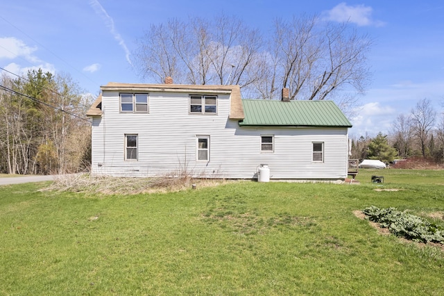 back of property with a yard, a chimney, and metal roof