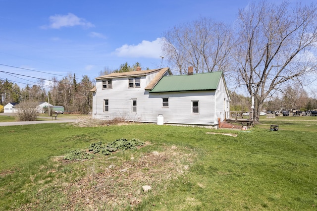 back of property with a lawn and a chimney