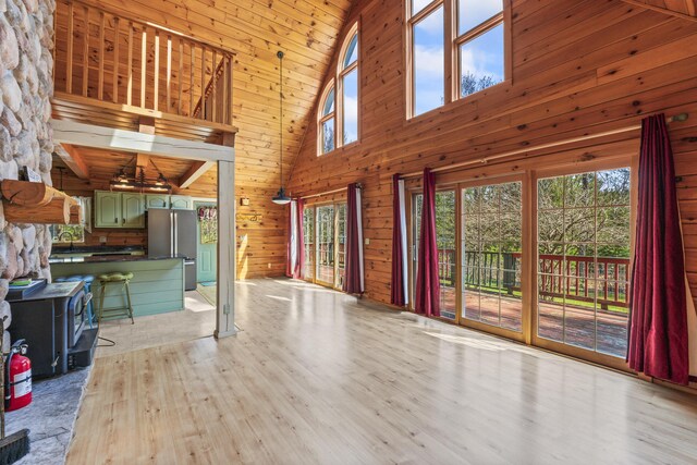48 Thistle Ln, Sidney, ME 04330 - unfurnished living room featuring high vaulted ceiling, light wood-style floors, wood walls, and a sink