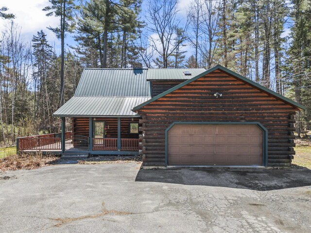 48 Thistle Ln, Sidney, ME 04330 - log cabin featuring log exterior, driveway, metal roof, a porch, and a garage