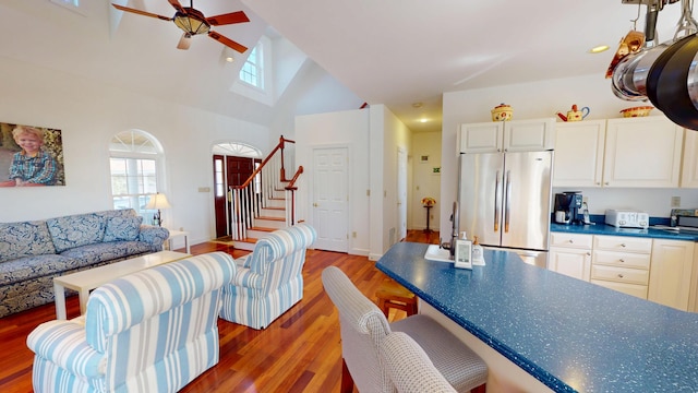 living room with light wood finished floors, recessed lighting, high vaulted ceiling, stairs, and a ceiling fan