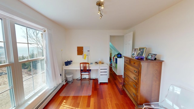 office with rail lighting, wood finished floors, a healthy amount of sunlight, and baseboard heating