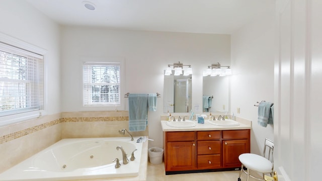 bathroom with a jetted tub, plenty of natural light, and a sink