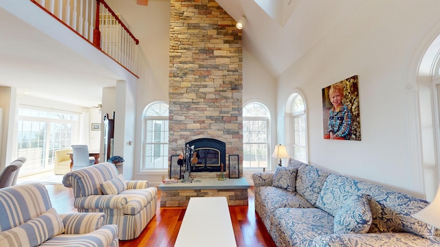 living area featuring high vaulted ceiling, a fireplace, and wood-type flooring