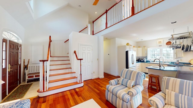 living room featuring recessed lighting, stairs, a towering ceiling, a skylight, and wood finished floors