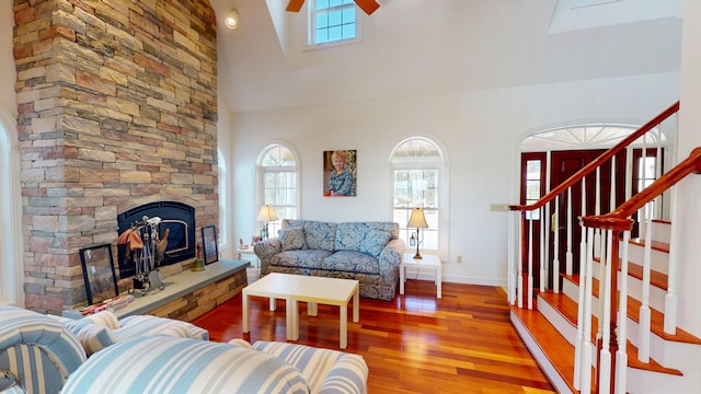 living area with plenty of natural light, high vaulted ceiling, wood finished floors, and a fireplace