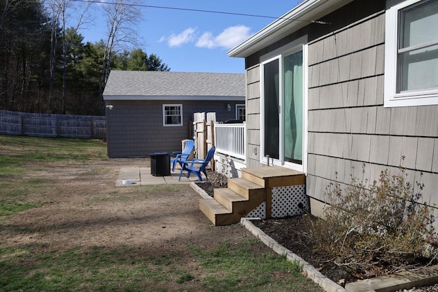 exterior space featuring fence, an outdoor fire pit, and roof with shingles