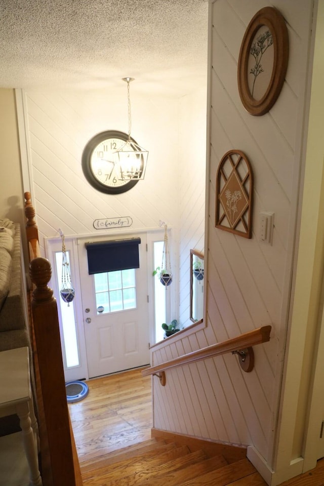entrance foyer featuring a textured ceiling, light wood-style flooring, and a chandelier