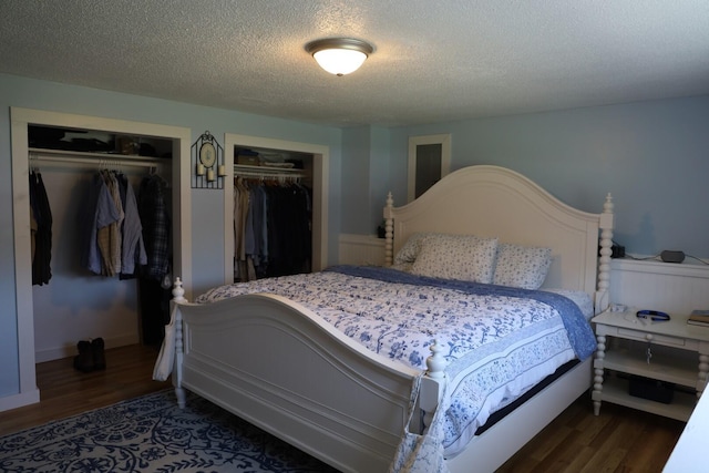 bedroom with a textured ceiling, multiple closets, and wood finished floors