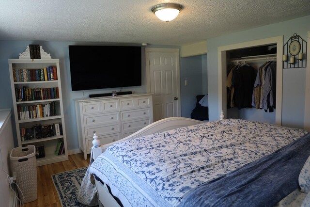 bedroom with a textured ceiling, wood finished floors, and a closet