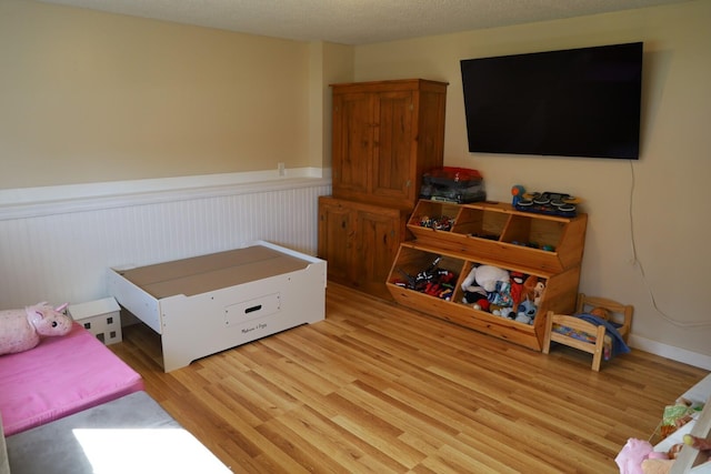 bedroom featuring light wood-type flooring and a wainscoted wall