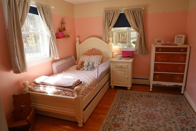 bedroom featuring a baseboard heating unit and wood finished floors