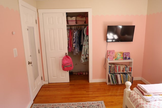 bedroom featuring baseboards, light wood-type flooring, and a closet