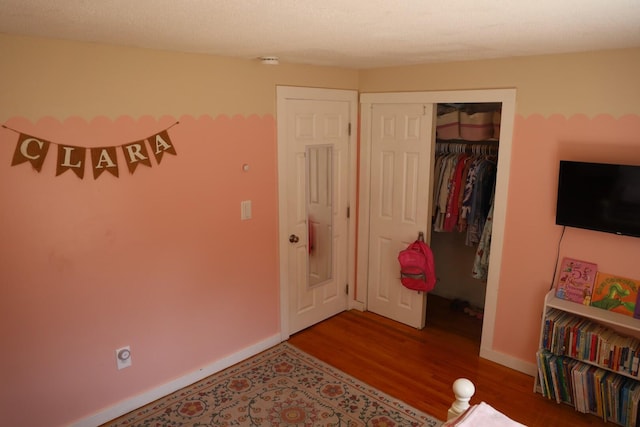 bedroom with baseboards, wood finished floors, and a closet