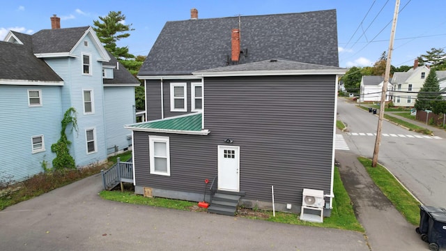 back of property featuring a chimney, entry steps, and metal roof