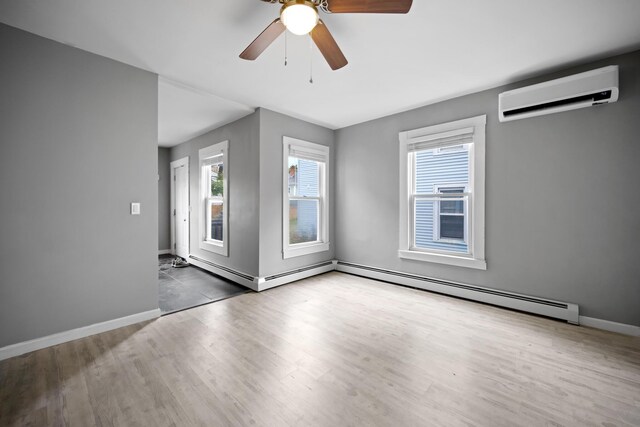 unfurnished room featuring a wall mounted air conditioner, ceiling fan, baseboards, baseboard heating, and wood finished floors