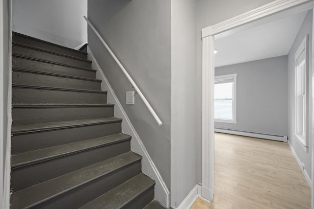 stairway featuring a baseboard radiator, wood finished floors, and baseboards