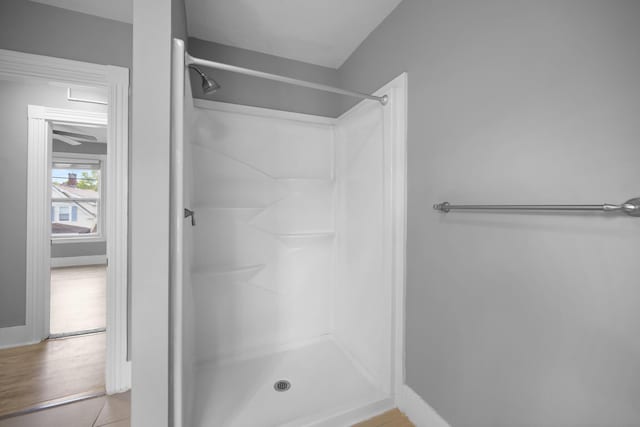 full bathroom with a shower stall and baseboards