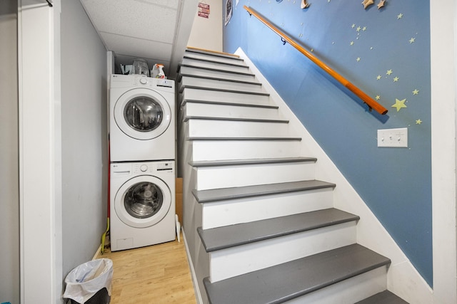 laundry area with stacked washer and clothes dryer, wood finished floors, and laundry area