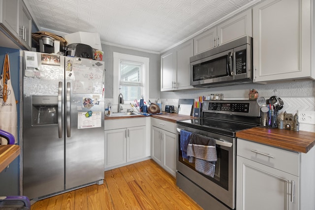 kitchen featuring a sink, wood counters, stainless steel appliances, and light wood-type flooring