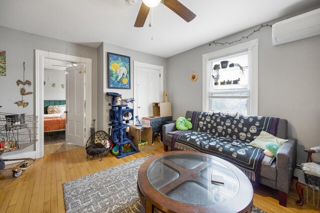 living area with hardwood / wood-style flooring, a wall mounted air conditioner, and a ceiling fan