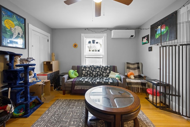 living area with a wall unit AC, ceiling fan, and hardwood / wood-style flooring