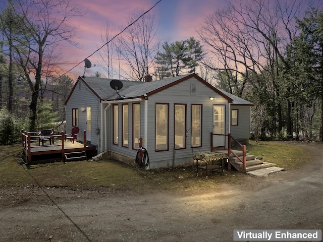 back of property at dusk with a deck and a chimney