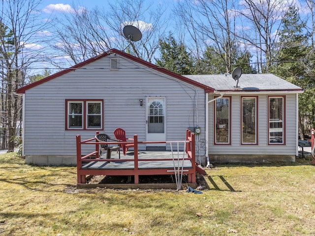 rear view of property featuring a lawn and a deck