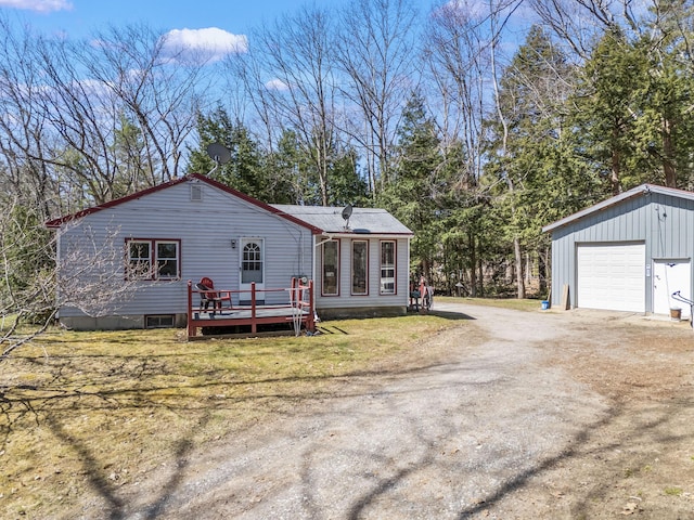 exterior space with a deck, an outbuilding, dirt driveway, and a detached garage