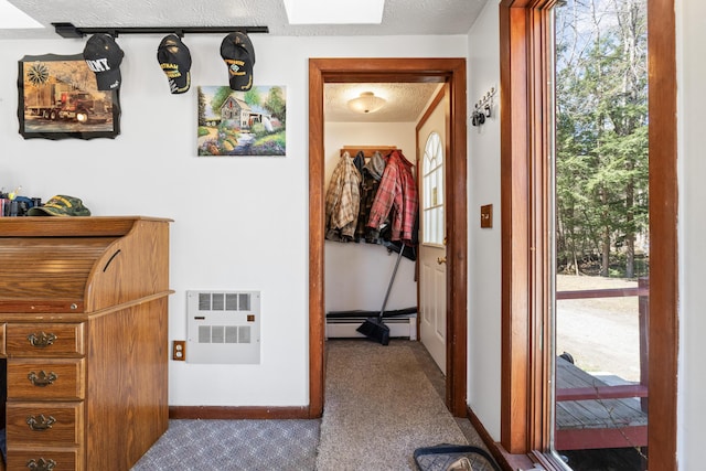 hallway featuring baseboards, baseboard heating, a wealth of natural light, and carpet floors