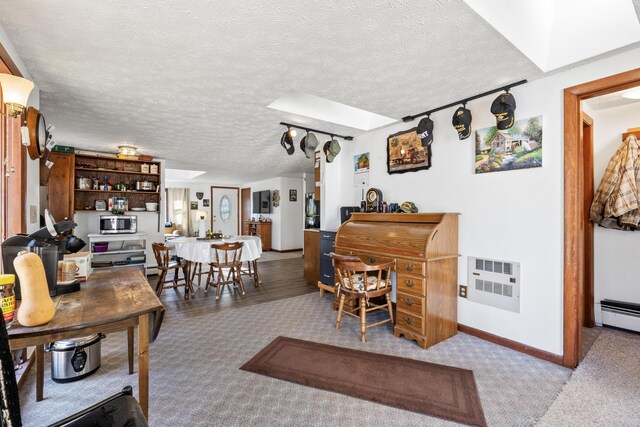 interior space with baseboards, a skylight, a baseboard heating unit, and a textured ceiling