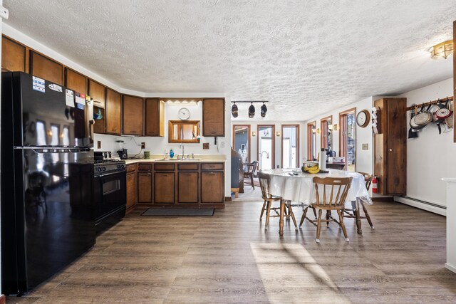 kitchen with a baseboard heating unit, black appliances, and a textured ceiling