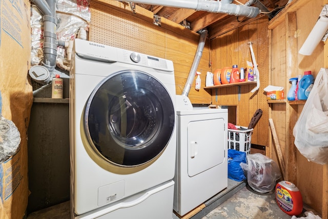 washroom with washing machine and dryer, wood walls, and laundry area