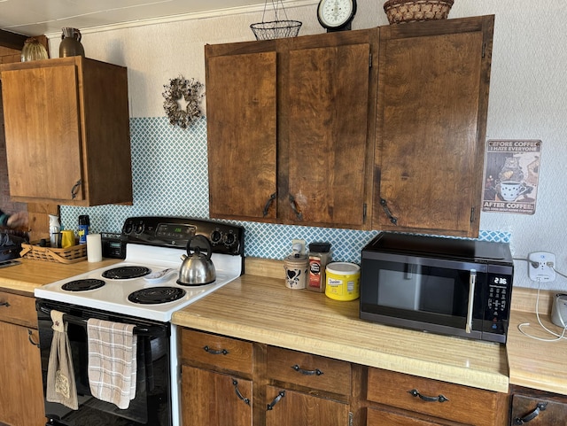 kitchen with tasteful backsplash, black microwave, range with electric cooktop, and light countertops