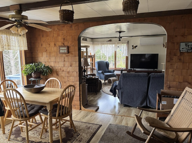 dining area featuring a wealth of natural light, light wood finished floors, and arched walkways