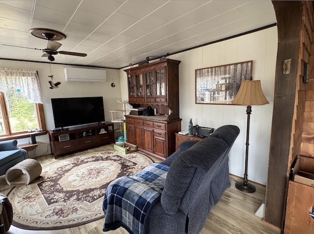 living room featuring light wood-type flooring, a wall unit AC, and a ceiling fan