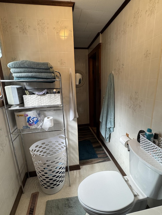 bathroom featuring tile walls, visible vents, and toilet