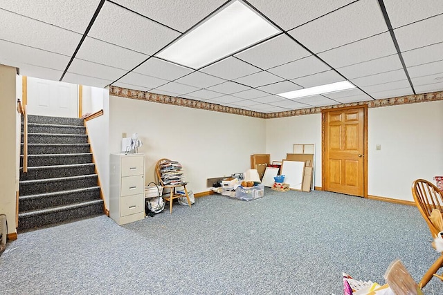 finished basement featuring stairway, a paneled ceiling, carpet flooring, and baseboards
