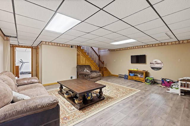 living area with visible vents, wood finished floors, baseboard heating, baseboards, and stairway