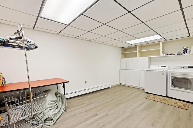 clothes washing area with washing machine and dryer, a baseboard radiator, light wood-style floors, baseboards, and laundry area