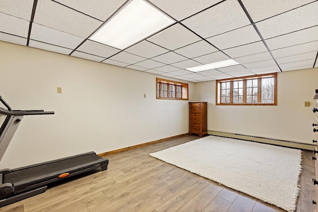 exercise area with a baseboard heating unit, wood finished floors, and baseboards
