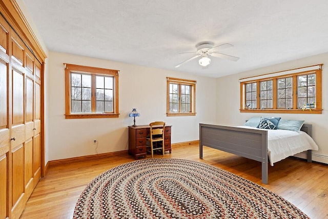 bedroom featuring multiple windows, baseboards, and light wood-style floors