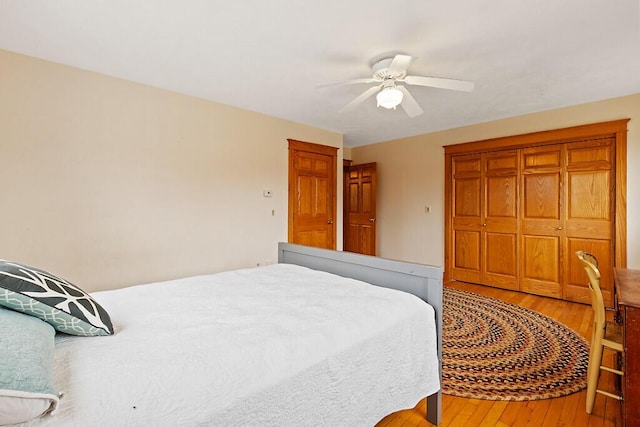 bedroom with hardwood / wood-style floors, a ceiling fan, and a closet