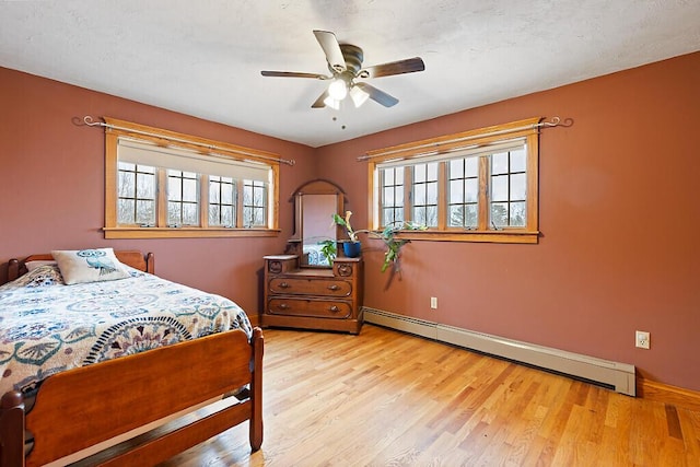 bedroom featuring baseboard heating, wood finished floors, and multiple windows