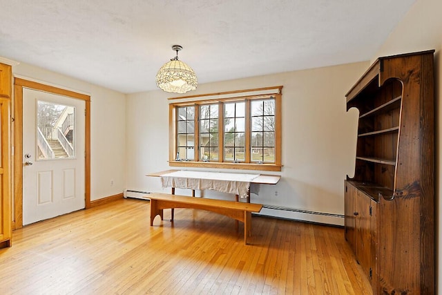 dining space with light wood-style floors, a healthy amount of sunlight, a baseboard heating unit, and baseboards