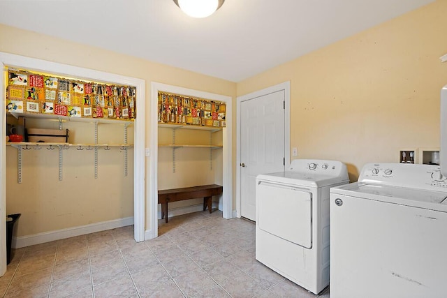 clothes washing area featuring light tile patterned floors, washing machine and dryer, laundry area, and baseboards