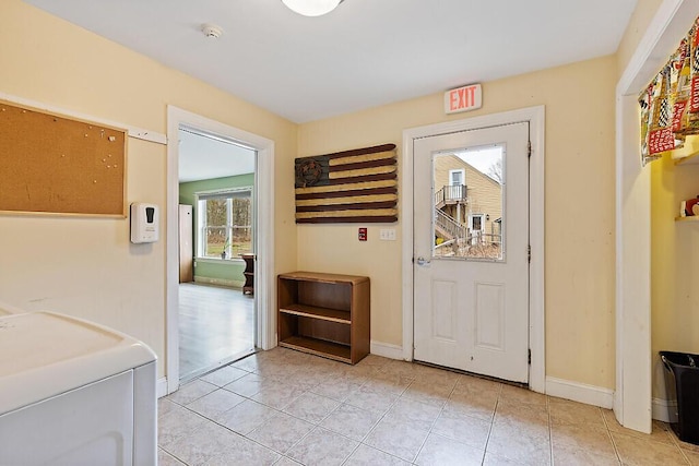 doorway to outside featuring light tile patterned flooring, washer / clothes dryer, and baseboards