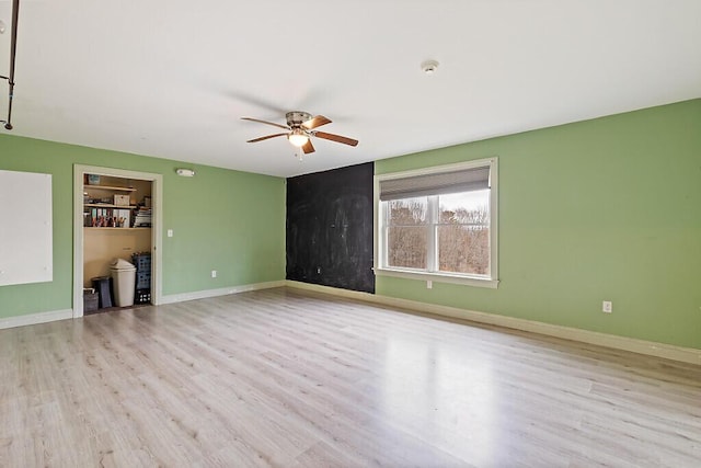 spare room with a ceiling fan, wood finished floors, and baseboards