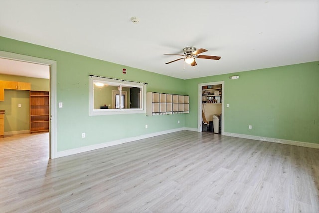 unfurnished living room featuring ceiling fan, baseboards, and light wood-style floors